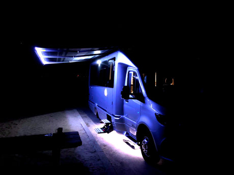 Illuminated rv rental at night, with an extended awning and bright underbody lights. Ready for comfy night camping.