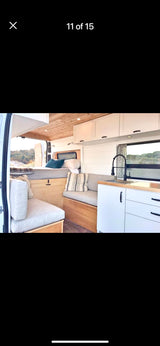 Modern RV rental interior: kitchen, bed, & spacious living area in a camper van.
