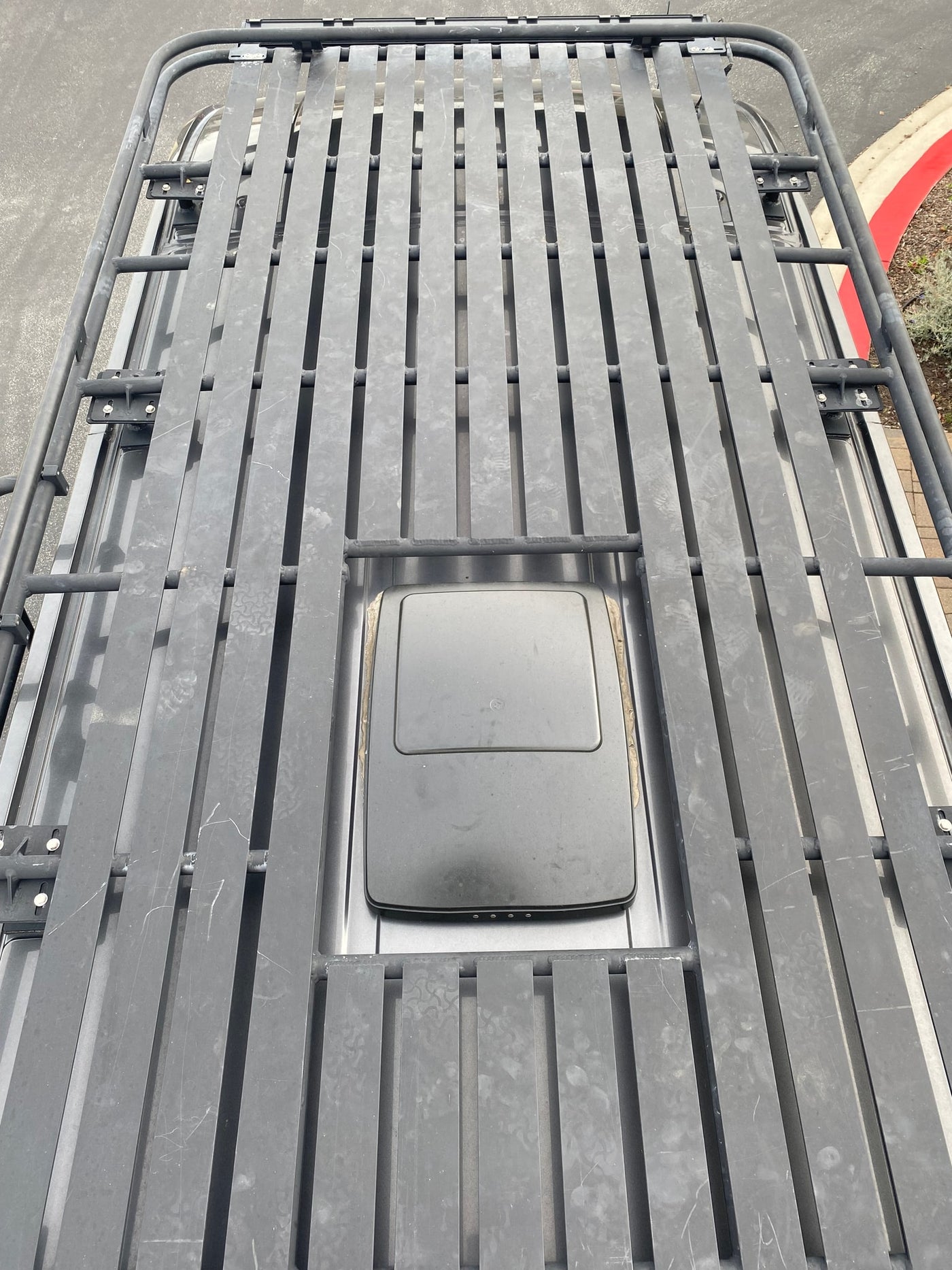 Overhead view of an RV rental roof with a heavy-duty roof rack and a mounted satellite dish for connectivity. — photo 18