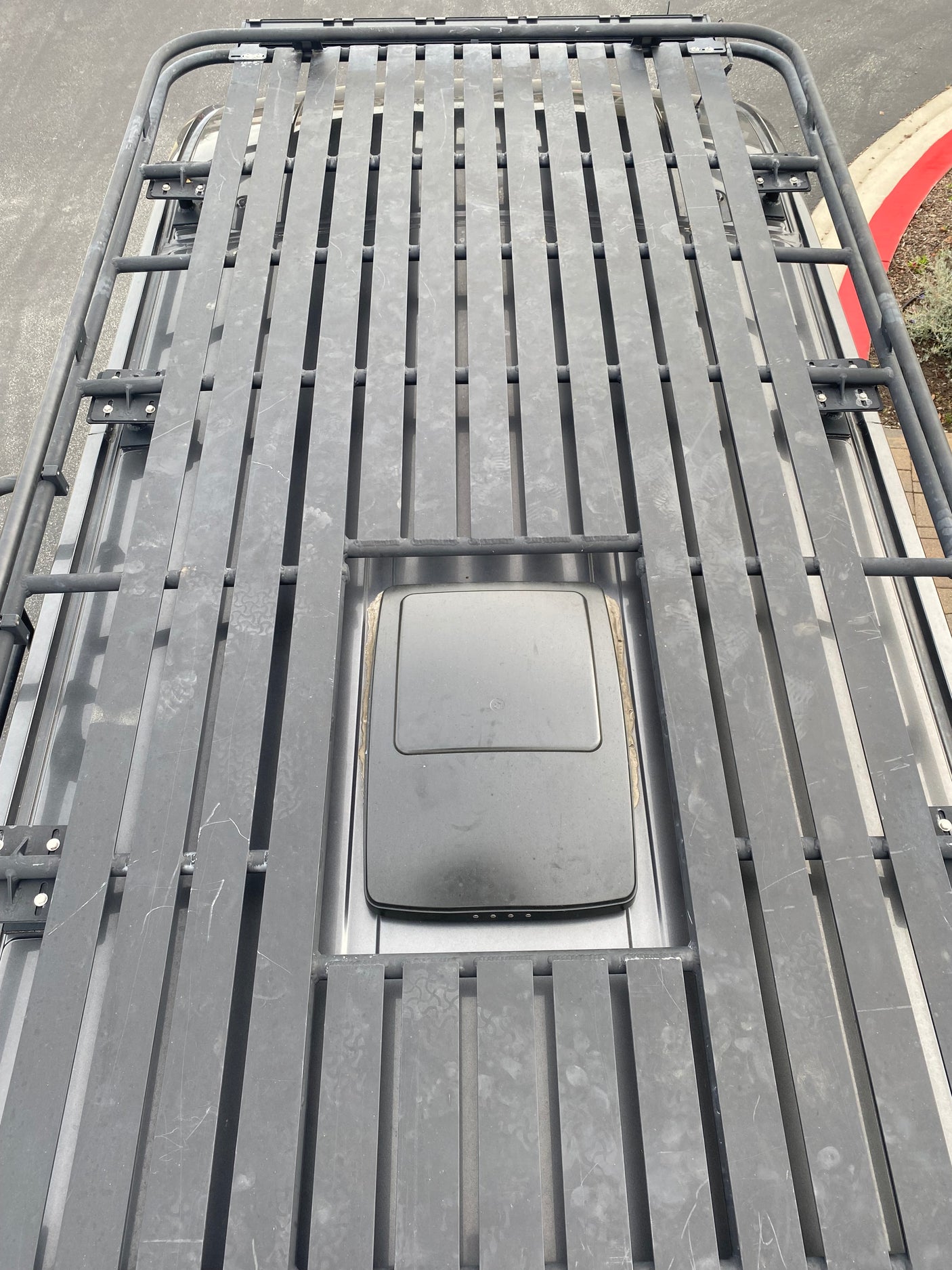 Overhead view of an RV rental roof with a heavy-duty roof rack and a mounted satellite dish for connectivity.