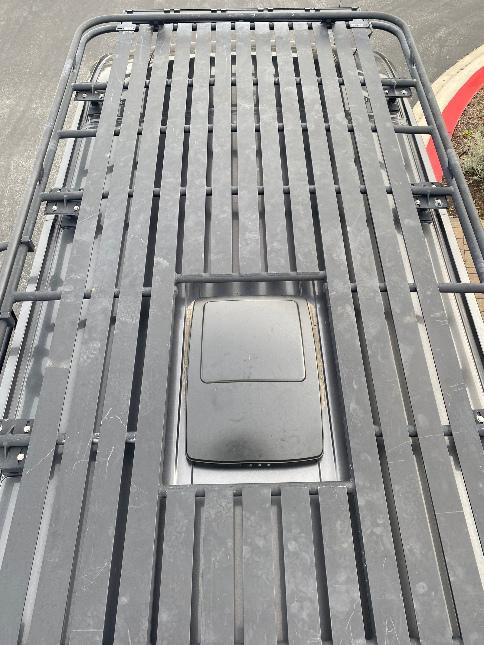 Overhead view of an RV rental roof with a heavy-duty roof rack and a mounted satellite dish for connectivity.