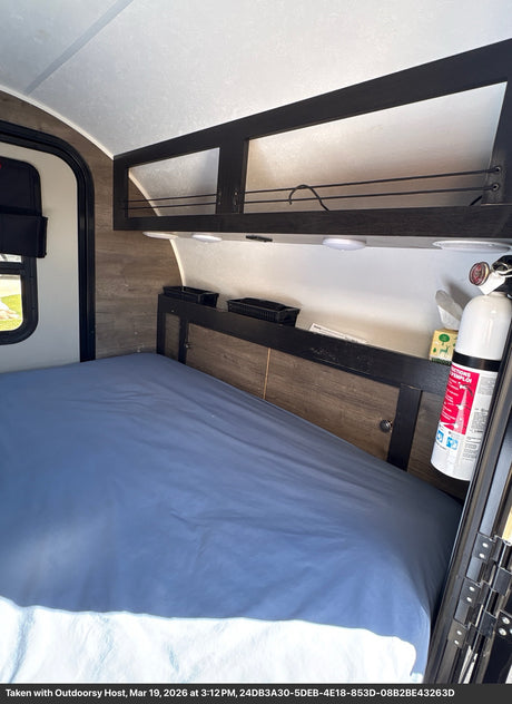 RV rental interior with a bed, overhead storage, and fire extinguisher for safety.