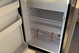 Clean, empty rv rental refrigerator. Wire shelves and strapped clear bins are ready for your travel provisions.