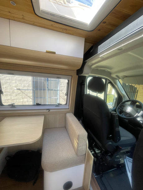 Spacious RV rental interior: dining area, overhead cabinets, driver's cab, & skylight.