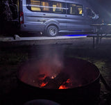 Cozy night camping with an RV rental, glowing campfire, and picnic table. Perfect for outdoor adventures under the stars.