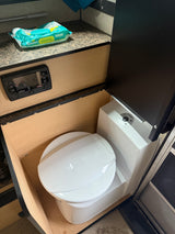 Compact RV rental bathroom with a Dometic toilet, Pampers wipes, and a REDARC control panel for comfort on the go.