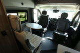 Spacious RV rental interior with swivel captain's chairs, a dinette table, and comfy seating, ready for adventure.