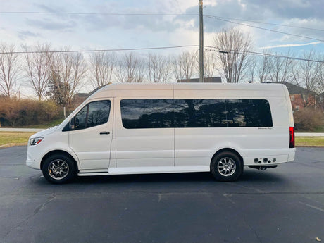 A white 'Ultimate Toys' luxury RV rental, a spacious conversion van with tinted windows, is parked on asphalt.