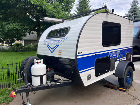 This white Classic Sunray teardrop RV rental with blue accents, a roof rack, and propane tank is ready for travel.