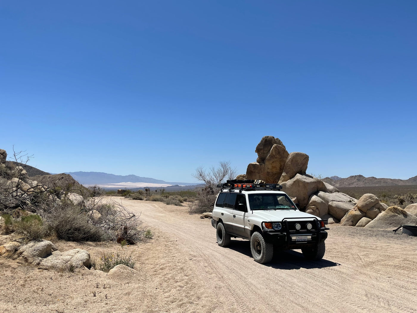 A white SUV on a sunny desert track amidst rocks, perfect for accessing remote sites beyond your RV rental. — photo 20