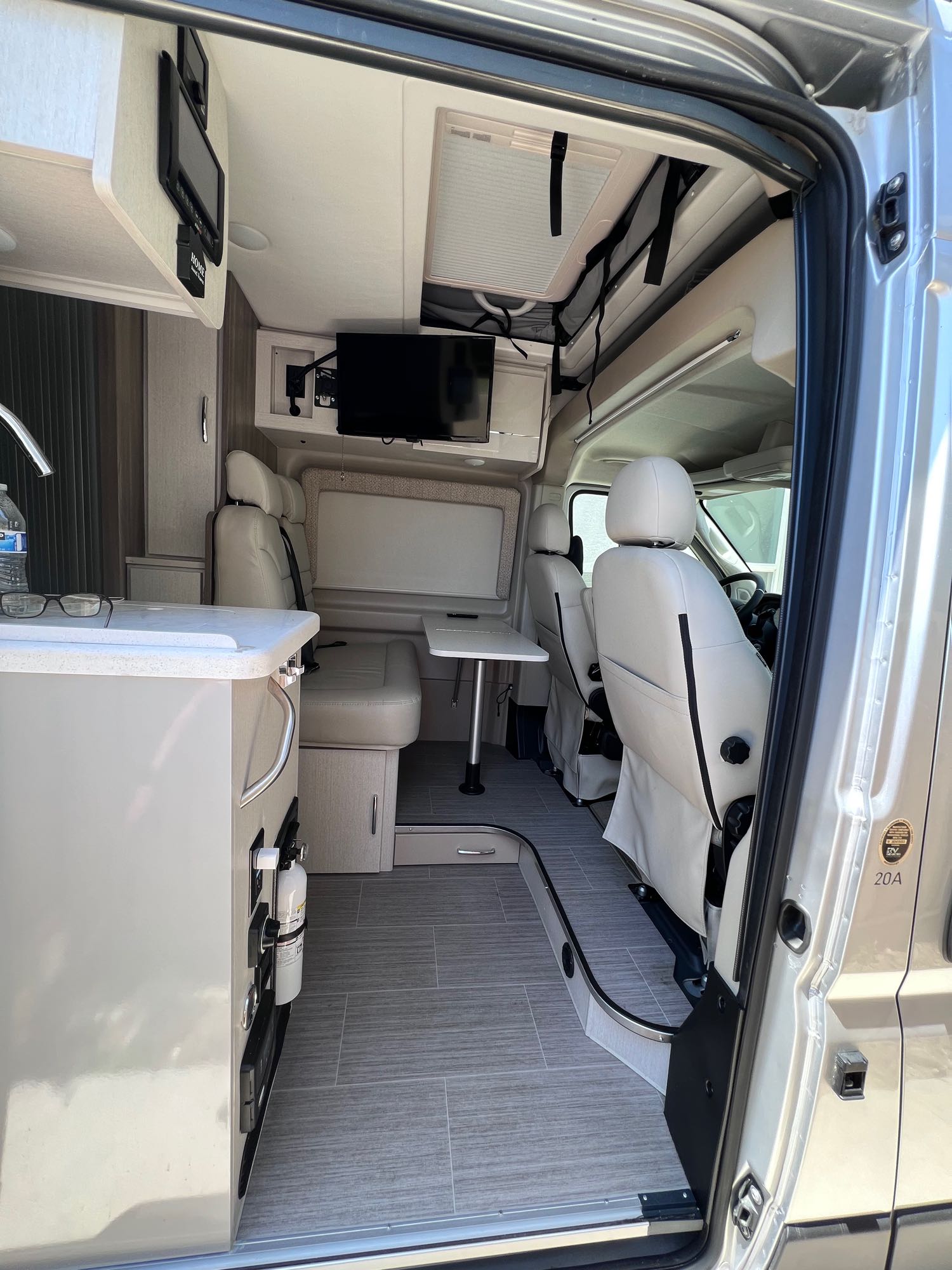Inside a modern **rv rental**: light gray interior with kitchen, dining table, and swivel front seats. Ready for your trip!