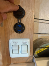 Inside an RV rental: Finger opens a USB QC 3.0 charger cover, with "Porch Light" and "Ceiling Light" switches below.