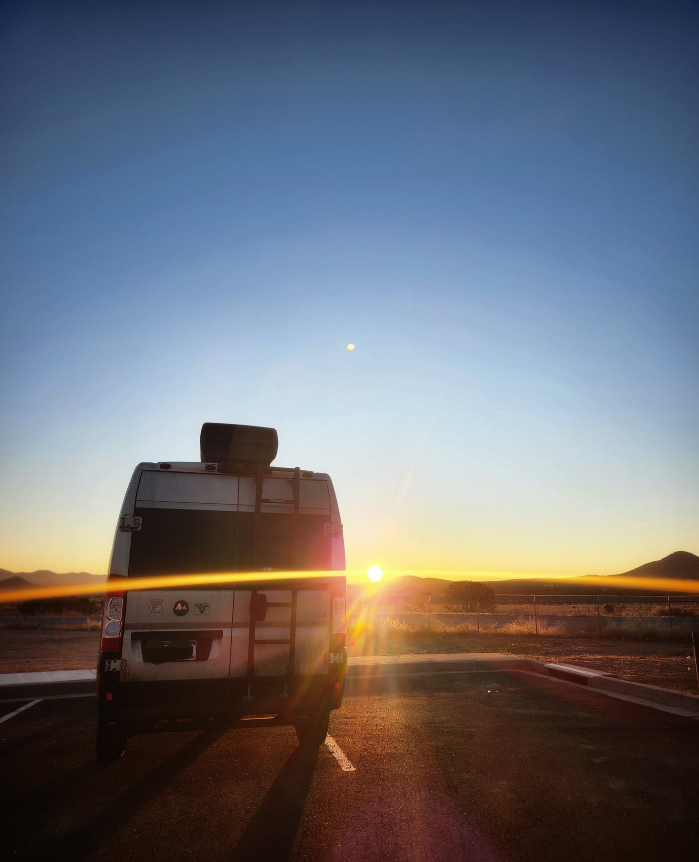 An RV rental parked, facing a vivid sunset over mountains. Epic road trip and travel views.
