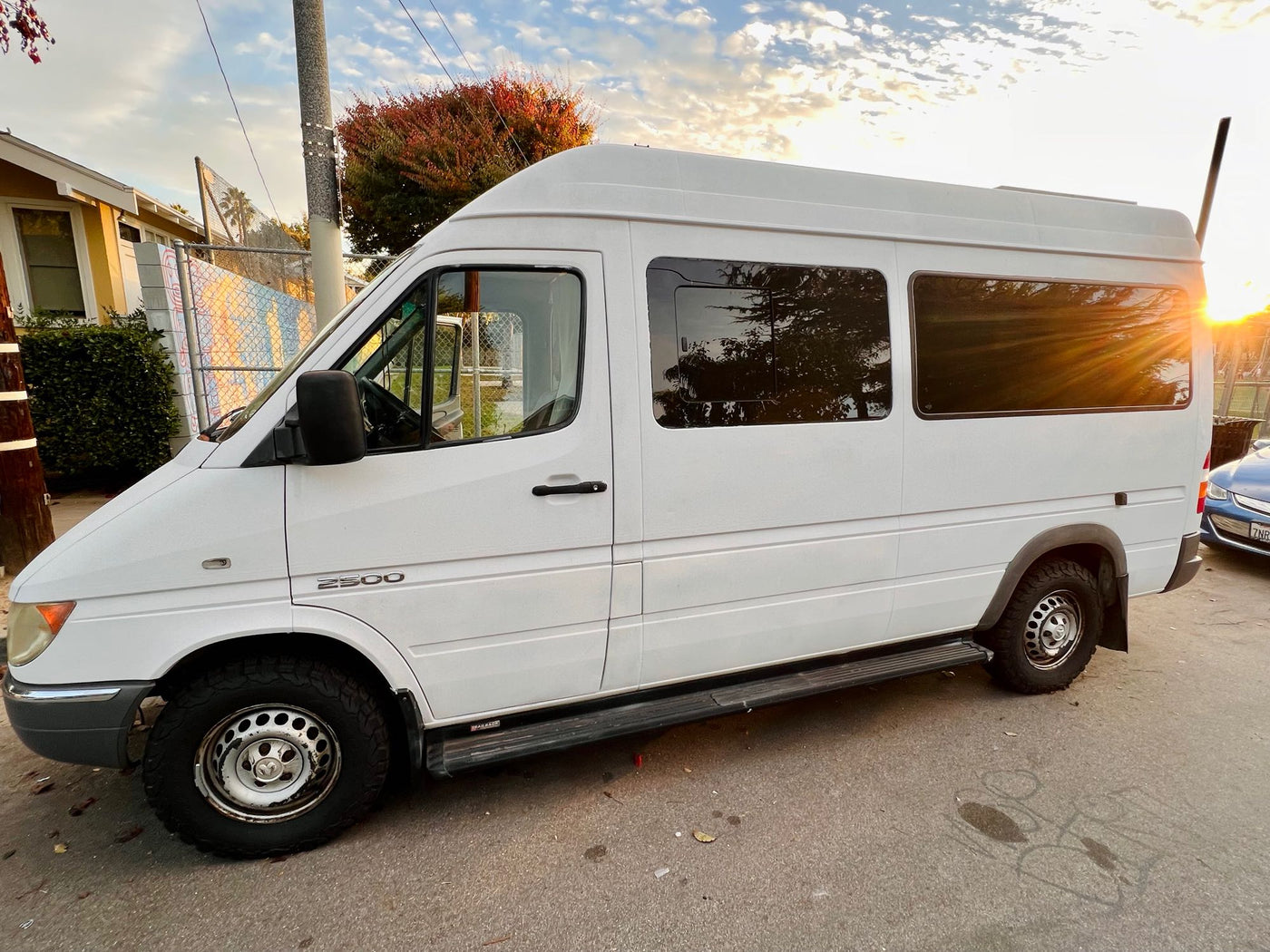  enjoys a stunning sunset by a hillside.|White Mercedes Sprinter 2500 camper van — photo 5