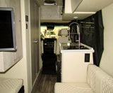 View inside a modern RV rental. Features include a galley kitchen, comfy seating, TV, and front cabin view.