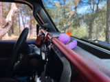A purple rubber duck sits on the dashboard of an RV rental, next to a red grab bar, ready for scenic drives.