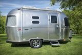 This shiny Airstream Caravel travel trailer, an ideal rv rental, is parked on vibrant green grass outdoors.