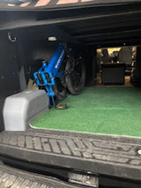 Folded blue e-bike stored in an RV rental cargo area with green turf. Ready for adventure!