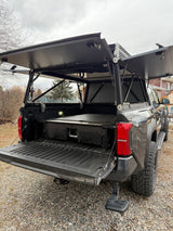 Tacoma truck bed, fitted with an open overland camper and storage, offers a compact RV rental alternative for camping.