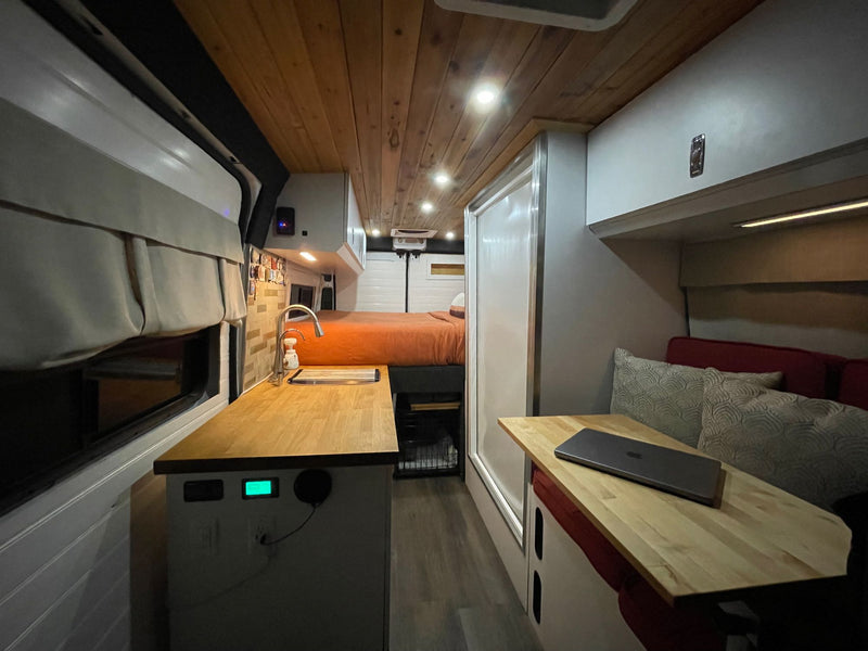  and dining space. Perfect for travel.|Two men and two dogs enjoy an rv rental camping trip. Relaxing by their camper van in a peaceful forest setting.|White RV rental van with two dogs peeking out the window — photo 4
