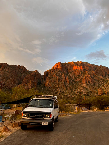 Stunning Texas sunset on rugged mountains with an RV rental campervan parked at a campsite. Perfect for outdoor adventure.
