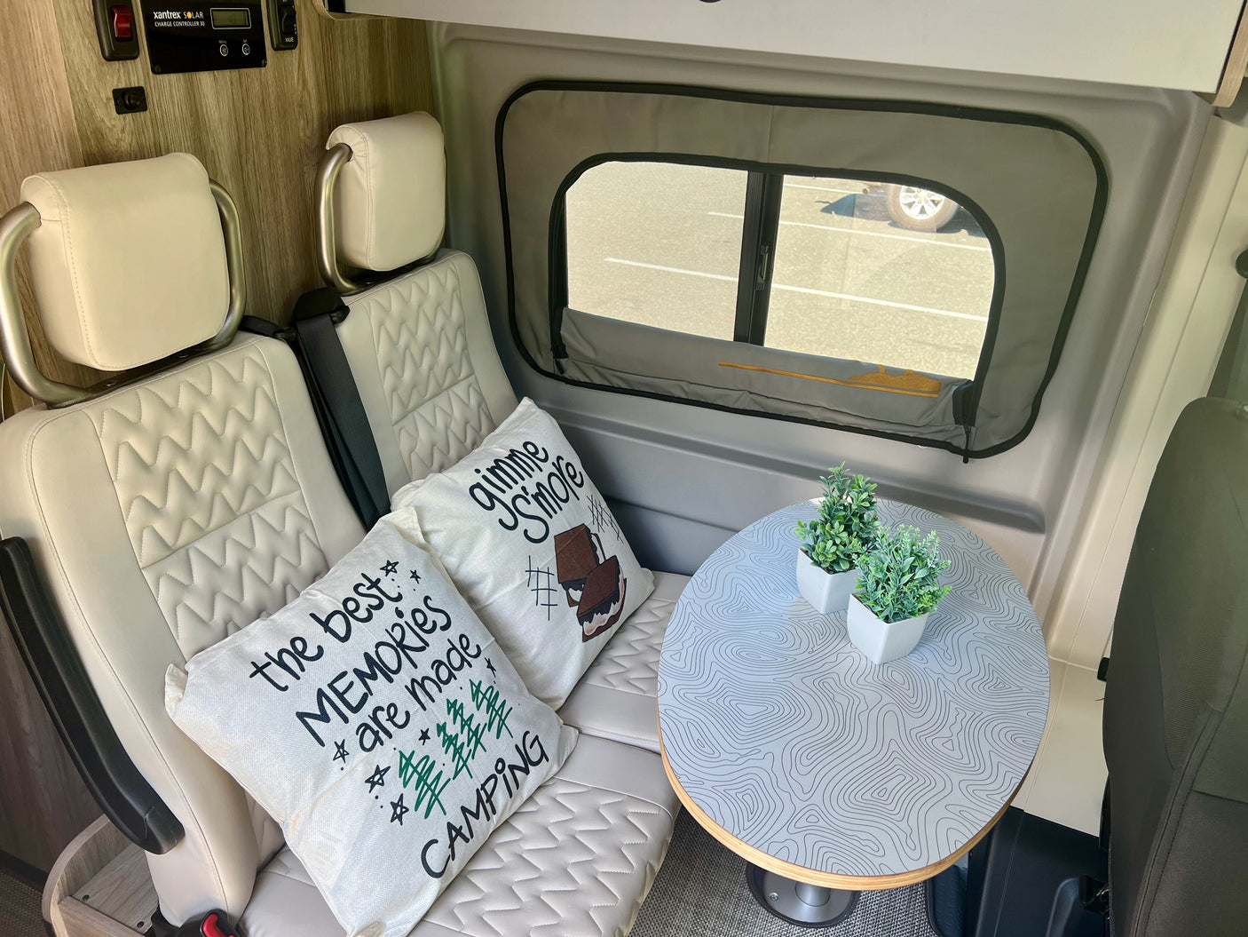 Cozy RV rental interior with comfy seating, camping-themed pillows, and a cool topo map table, perfect for your next adventure.