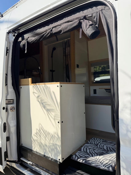 Explore this RV rental's modern interior via its open door. Features include a kitchenette, shower, and a practical top bug screen.