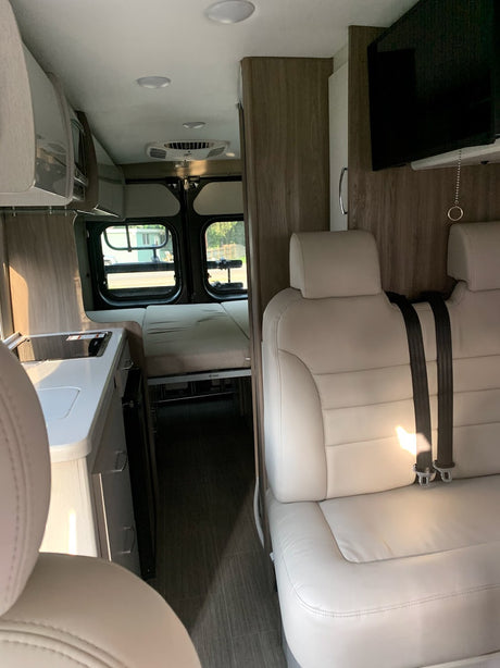 Inside this modern rv rental: kitchen, rear bed, and comfortable seating with TV.