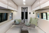 Spacious rv rental living area: A bright interior with opposite benches, a central table, overhead cabinets, and large windows.
