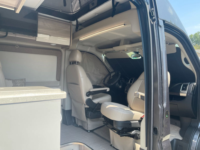 Explore this RV rental's cozy interior: swivel beige seats, compact kitchen, TV, and ambient lighting, ready for adventure. — photo 11