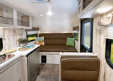 Bright RV rental interior with a functional kitchen, convertible sofa, and netted overhead storage. Perfect for road trips!