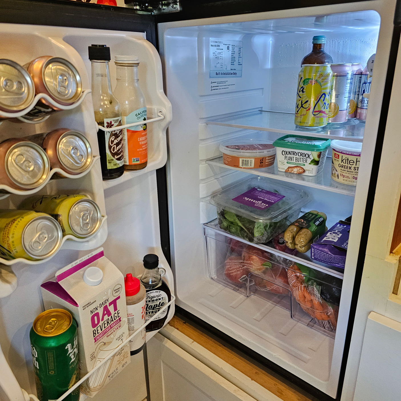 Well-stocked RV rental mini-fridge featuring sparkling water, oat milk, plant butter, and other fresh provisions.