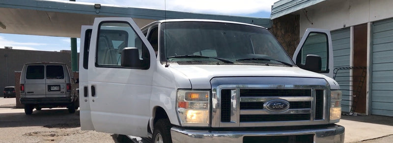 White Ford van with open doors parked near a grey van and storage units. Great for moving or an RV rental alternative.|White Ford van for RV rental — photo 1