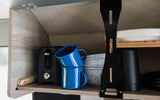 RV rental kitchen cabinet with a compact toaster, blue enamel mugs, bowls, and plates, ready for your adventure.