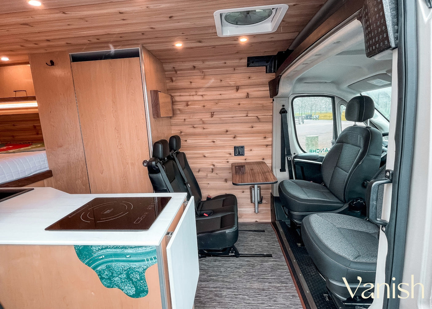 Detailed view of a modern RV rental interior, showcasing a compact kitchen, cedar walls, and versatile passenger seating.