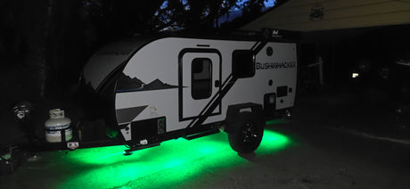 This Bushwhacker RV rental glows with green underglow lights at night, ready for your next outdoor adventure.