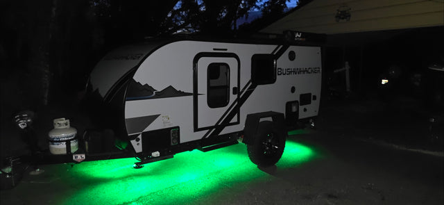 This Bushwhacker RV rental glows with green underglow lights at night, ready for your next outdoor adventure.