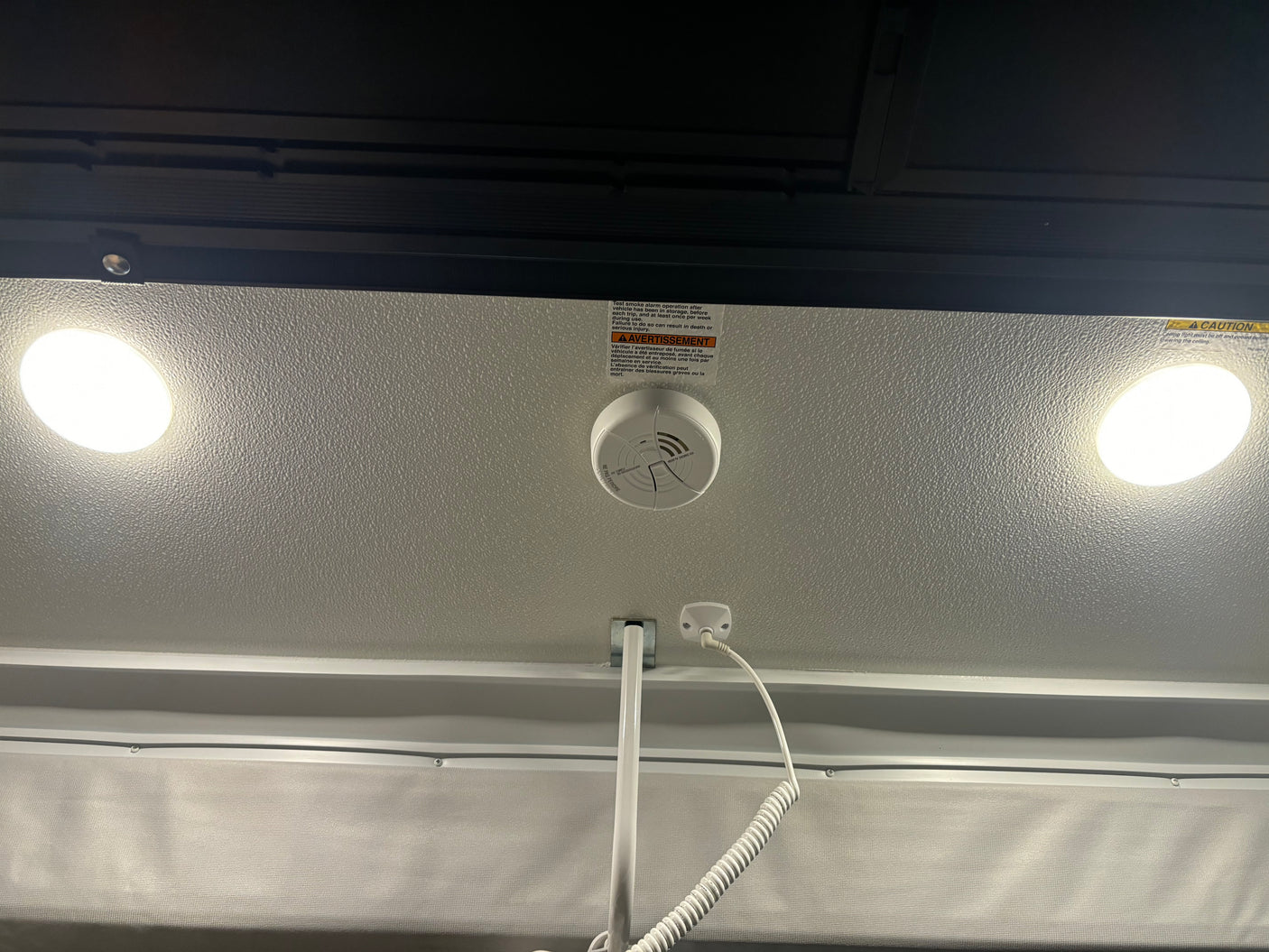 RV rental ceiling: Illuminated lights, a smoke detector, and important safety warnings for occupants.