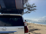 White Lexus GX 460 SUV with rooftop tent on a sunny beach, an ideal rv rental for oceanfront adventures.