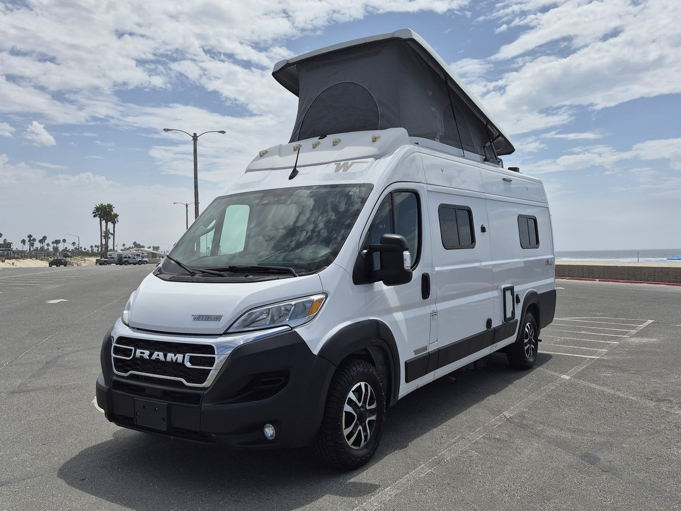 White Winnebago Solis pop-top camper van (rv rental) parked overlooking the ocean — photo 1