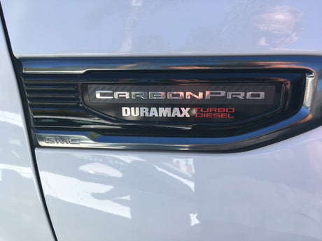 A white GMC truck fender displays its Carbon Pro, Duramax Turbo Diesel badge, perfect for your next rv rental adventure!