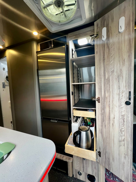 Spacious RV rental kitchen with a stainless fridge, pantry storage for a kettle & essentials. Modern and functional space.