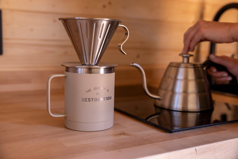 Hands pour hot water for pour-over coffee in an RV rental kitchen. A personalized mug and kettle are on a wooden counter. — photo 5