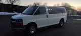 White camper van for RV rental, parked at sunset. Snow and bare trees in view.