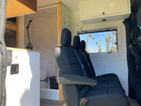 RV rental: Passenger seating, window with palm trees, and a compact kitchen/bathroom in a cozy mobile living space.