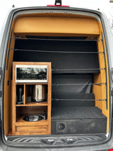 RV rental camper van with a built-in kitchenette (sink, microwave, coffee maker) and a modular bed/storage area inside.