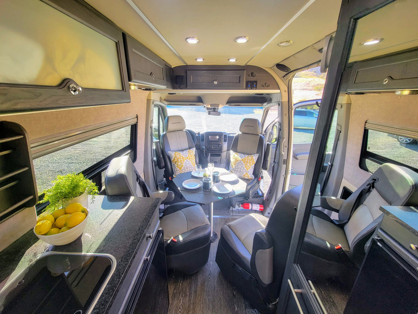 Inside a modern Roadtrek rv rental, showcasing its versatile living area with dining, kitchenette, and comfortable swivel seats.