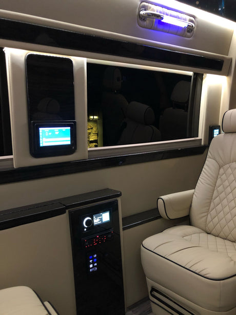 Luxury RV rental interior with cream quilted seats, advanced control panels, and blue accent lighting for ultimate comfort.
