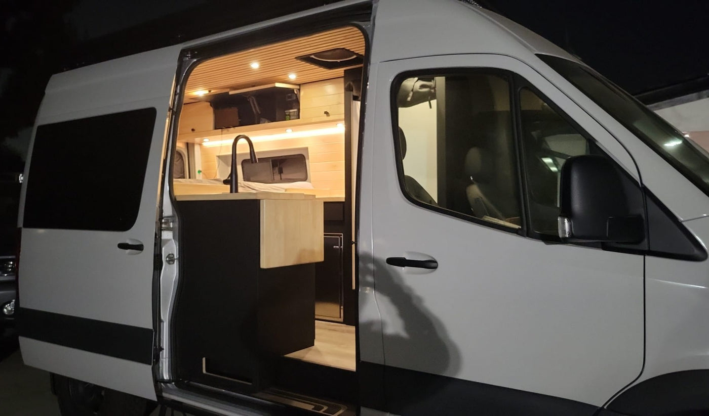  showing kitchen and wooden accents. Ideal for rv rental.|This sleek grey Mercedes Sprinter RV rental is perfectly equipped for off-road camping & adventure on scenic trails.|Cozy RV rental interior with a comfortable bed — photo 2
