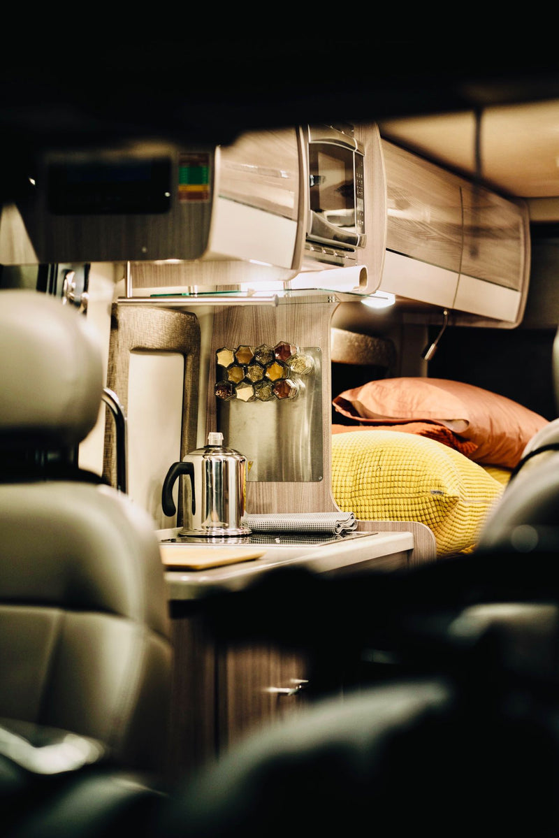  and natural light from overhead and side windows.|Cozy RV rental interior: a colorful bed next to a compact wet bath with toilet — photo 20